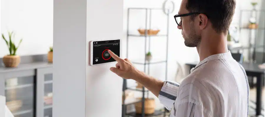 Een man bedient de alarmsystemen en andere slimme functies van zijn huis met behulp van een tablet